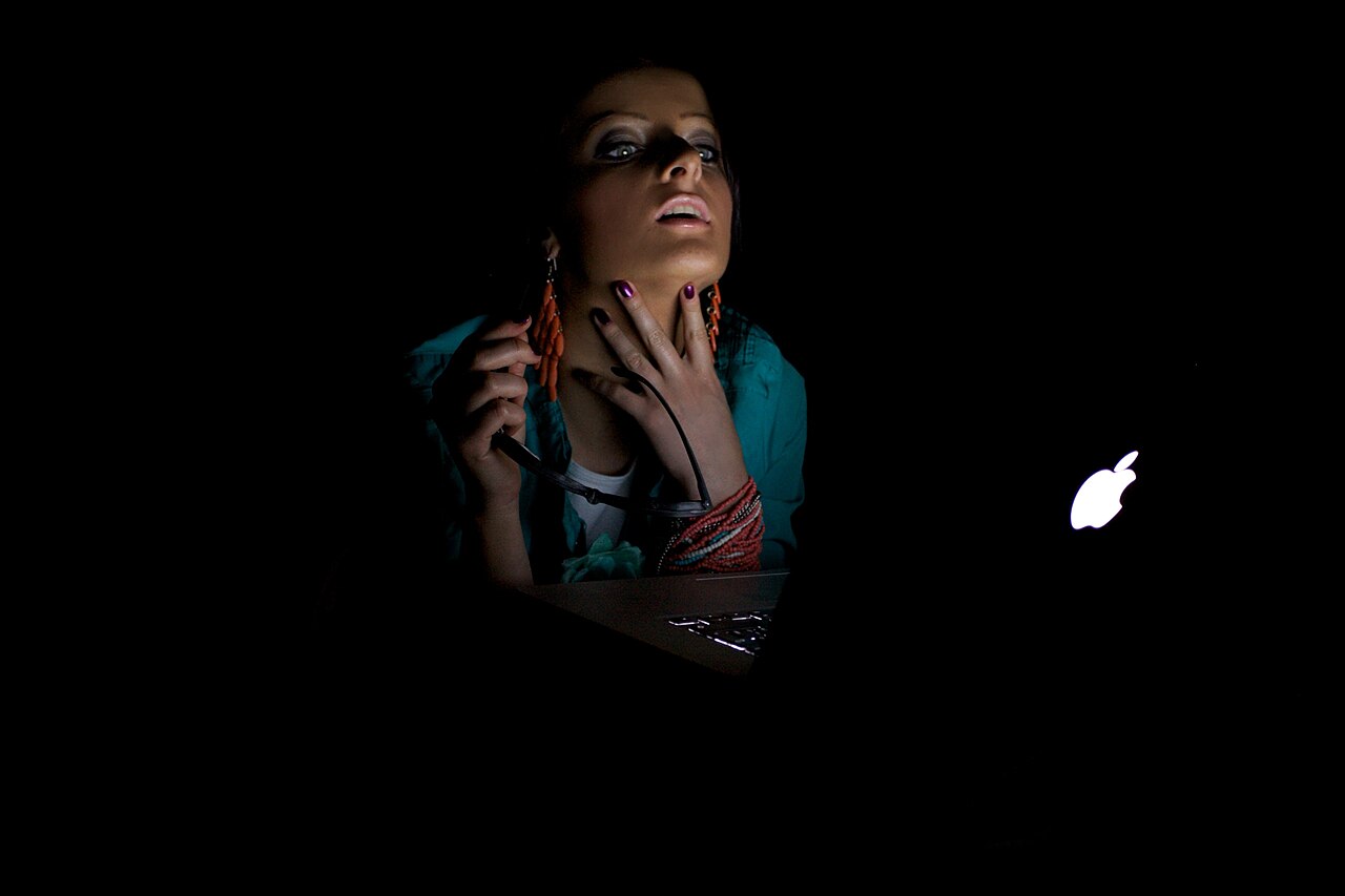 Femme devant un écran d'ordinateur dans la pénombre