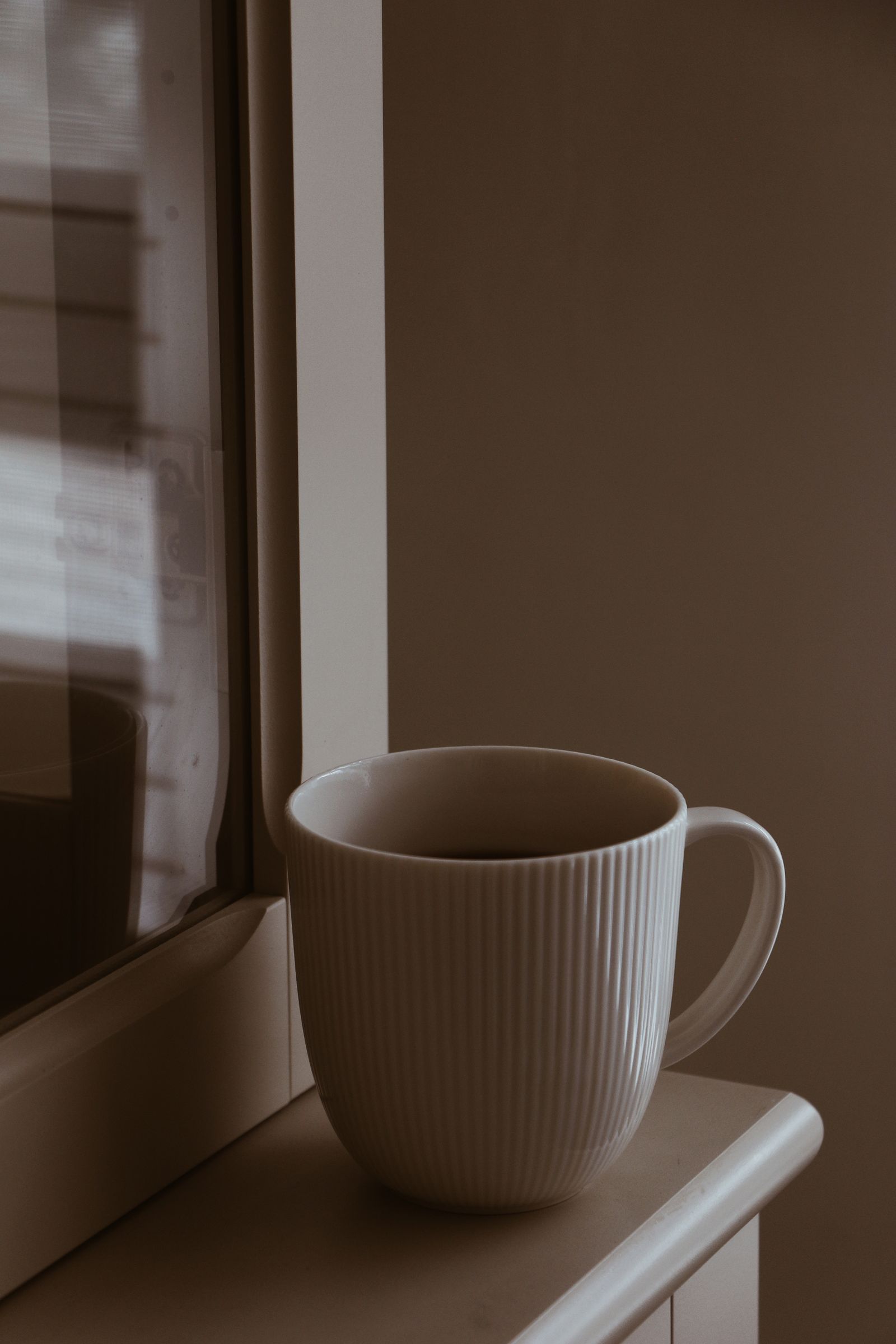 Tasse de café du matin posée près d'une fenêtre baignée de lumière