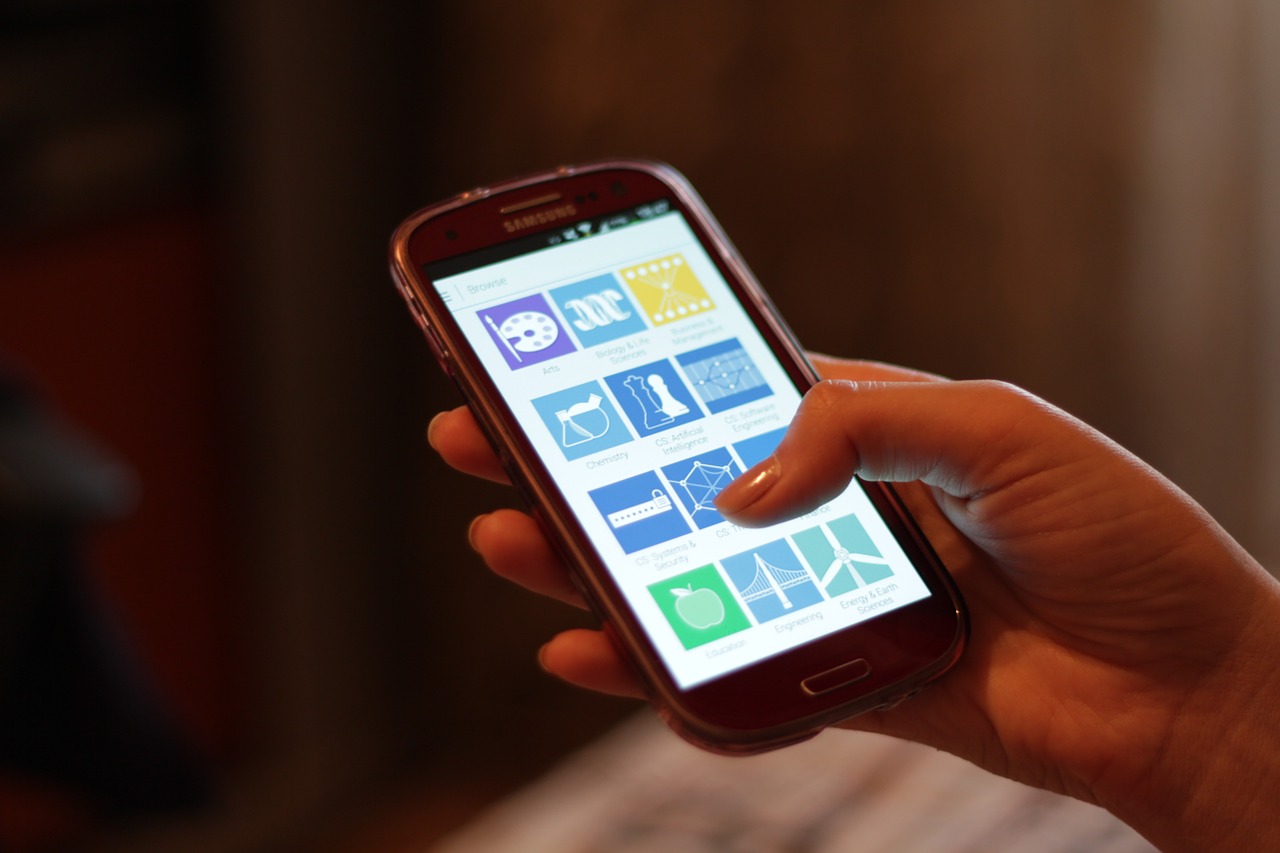 Main tenant un smartphone à l'écran allumé