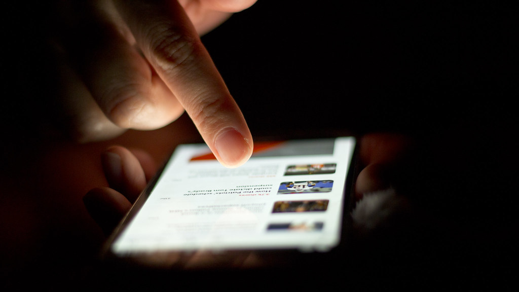 Main tenant un smartphone et faisant défiler l'écran